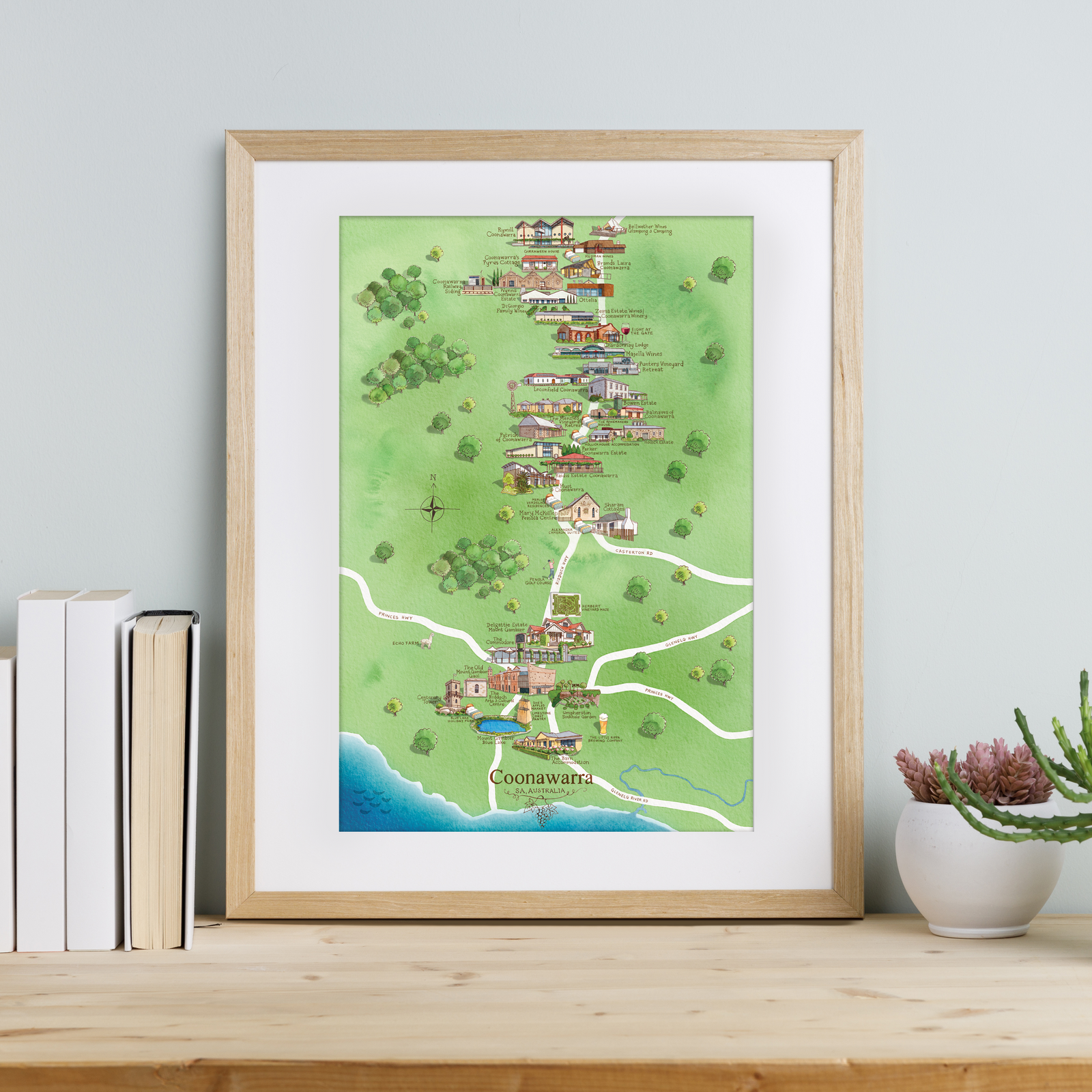Framed map of Coonawarra on a wooden surface with books and a plant.