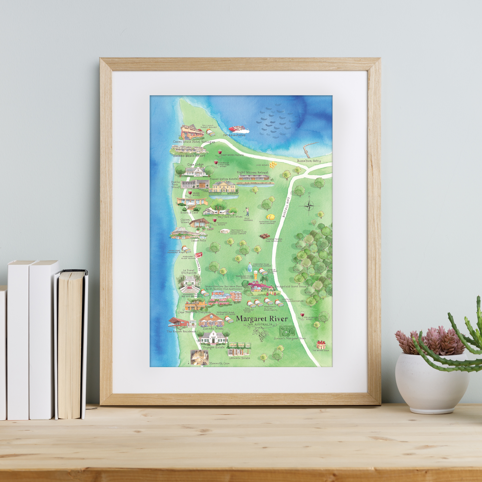 Framed map of Margaret River on a wooden surface with books and a plant.